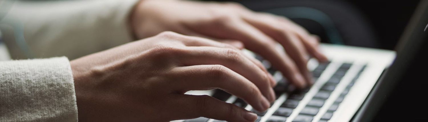 Hands typing on a laptop