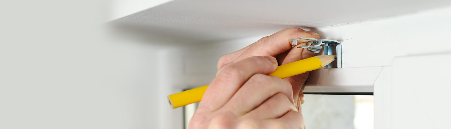 A workman marking points on a window fitting